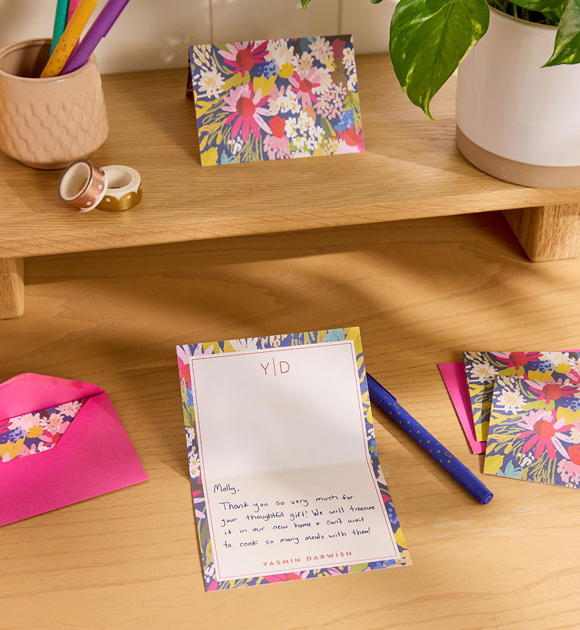 Personalized stationery set with floral notecards and envelopes on a wooden desk