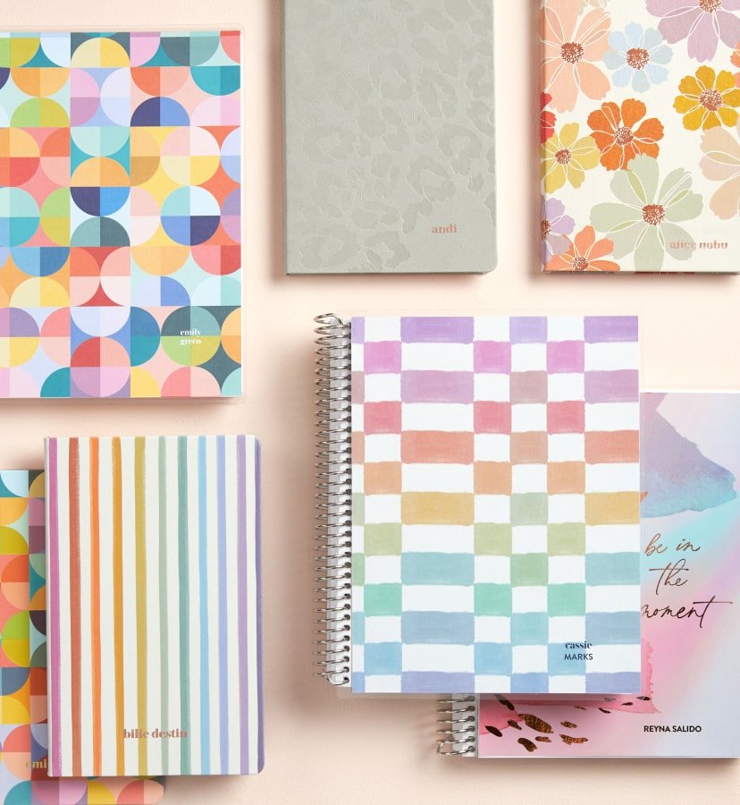overhead view of coiled and softbound notebooks featuring new designs. Click to shop now