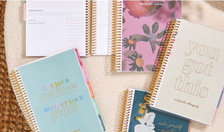 Coiled guided journals and notebooks on a table.