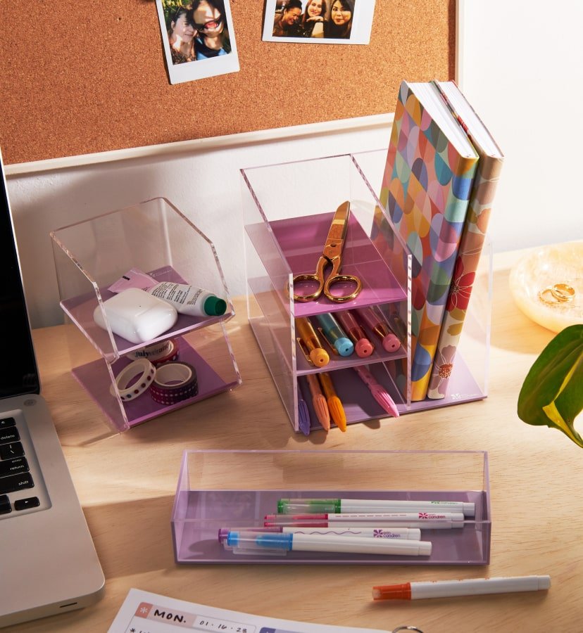overhead view of acrylic desk accessories filled with notebooks and writing tools