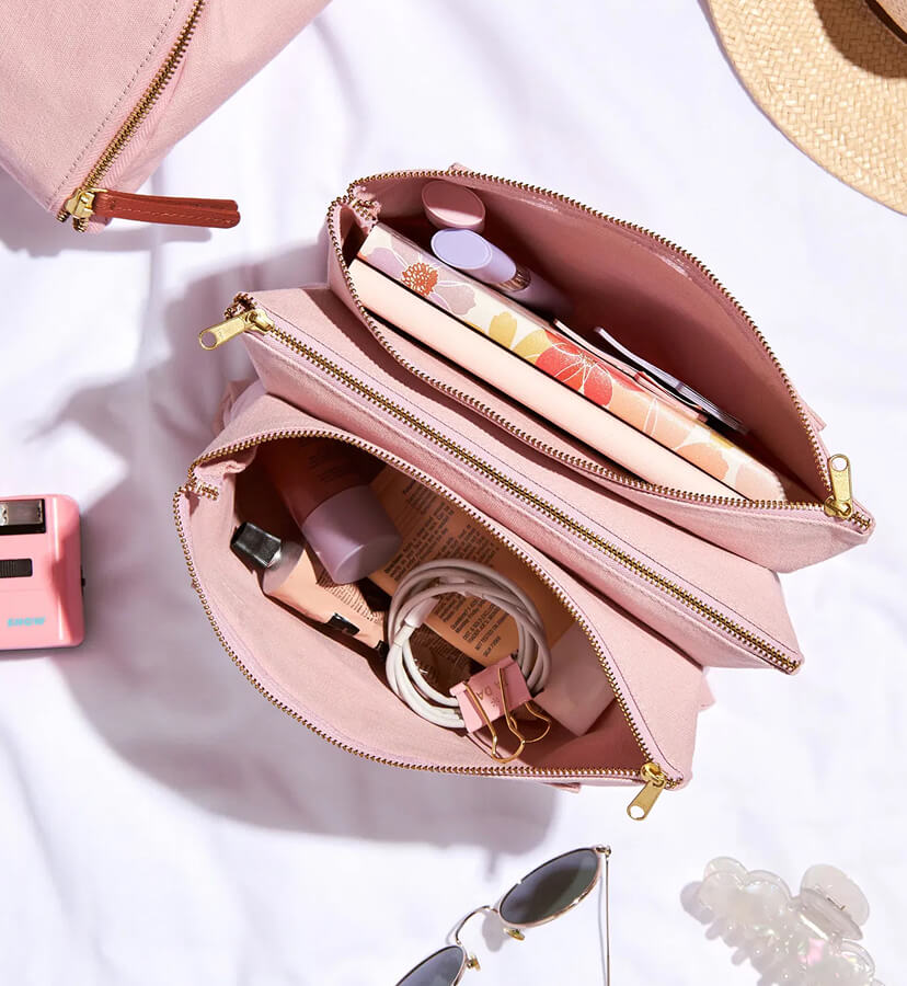 Image of an open Accordion Zipper Pouch filled with accessories on a desk.